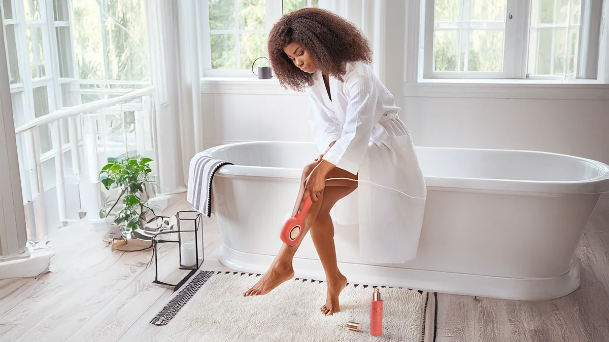 ipl hair removal at home, an African-american woman with beautiful legs in a spacious white bathroom